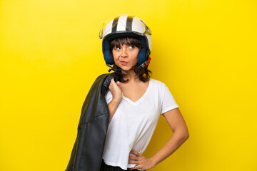 Young latin woman with a motorcycle helmet isolated on yellow background