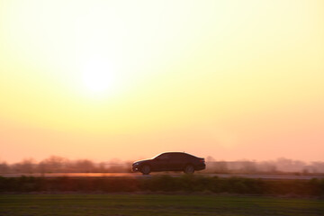 Car driving fast on intercity road at sunset. Highway traffic in evening