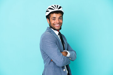 Young business Brazilian man with bike helmet isolated on blue background with arms crossed and looking forward