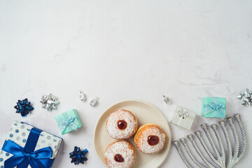 Jewish holiday Hanukkah background with traditional donuts, menorah and gift box. Top view, flat lay