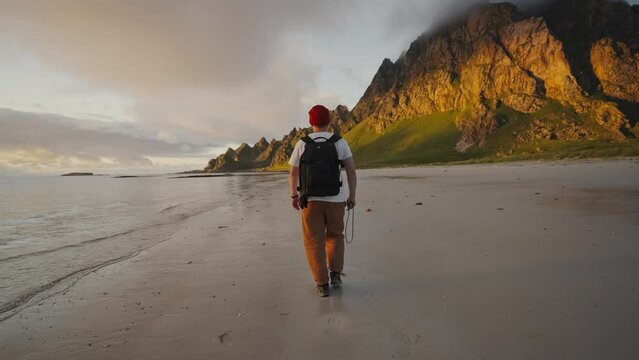 Professional photographer man with a backpack walks along the seashore, travel, adventure, Norway