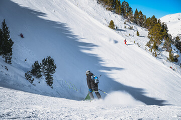 Skiers having fun on steep piste or ski slope in Pyrenees Mountains. Winter ski holidays in El Tarter, Grandvalira, Andorra
