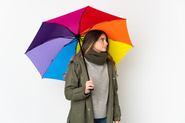 Young caucasian woman holding an umbrella isolated on white background looking to the side