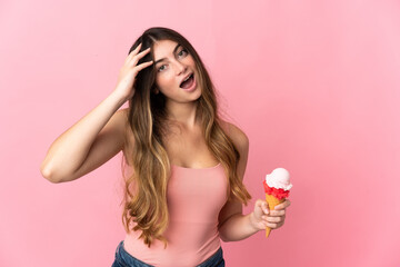 Obraz na płótnie Canvas Young caucasian woman with a cornet ice cream isolated on pink background with surprise expression