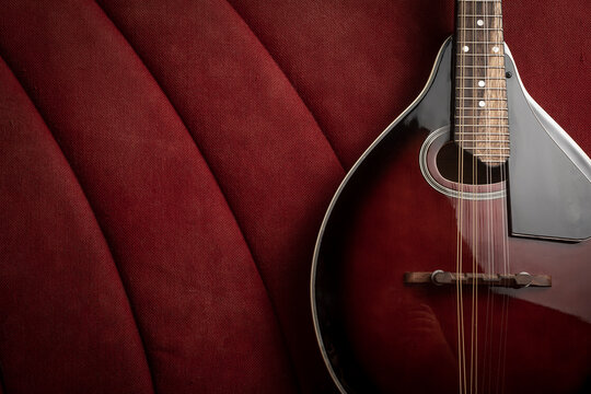 Background with mandolin leaning against a red sofa, plenty of room for text