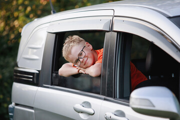 Blond boy in the car window have fun, laugh, rejoice.