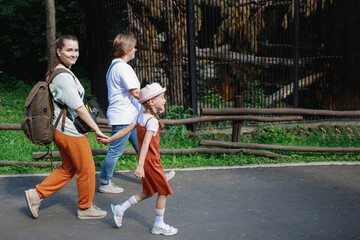 People with backpacks walk along the path in the summer park
