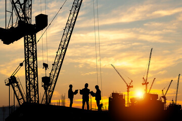 Fototapeta na wymiar Silhouette of Engineer and worker team on building site, construction site at sunset in evening time