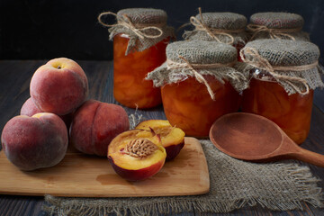 There are several fresh peaches on a cutting board, one of them cut in two.