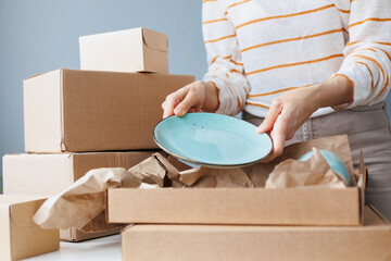 woman packs handmade plates into boxes. small business and entrepreneurship. a business woman sends...