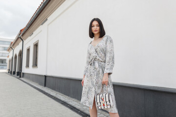 Fashion pretty brunette woman model in fashionable vintage flowers spring dress with trendy bag...