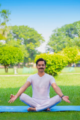 Young indian man doing yoga in park.