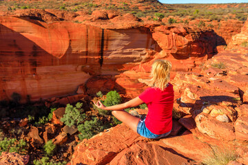 Peaceful woman doing yoga meditation in lotus pose at edge of Kings Canyon in Watarrka National...