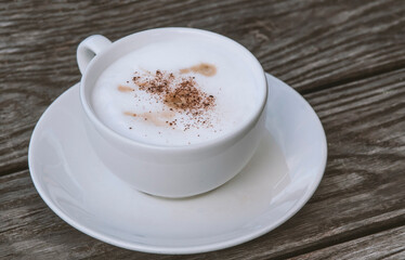 cup of coffee with foam on wooden table background