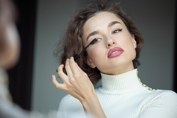 Portrait of a beautiful young woman applying makeup