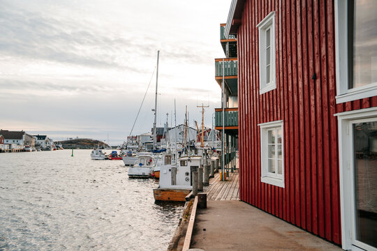 Henningsvaer, Lofoten Islands, Norway - 25.9.2022 - Red facade of a souvenir shop with a white bench and flowers in the Lofoten Islands.