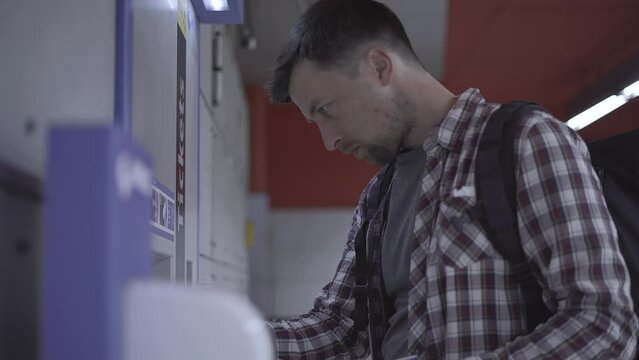 Man buys fare from vending machine in Munich, Germany. Male using ticket machine. Passenger buys a pass from a terminal device. Ticket terminal machine. Payment for public transport in Deutschland. 