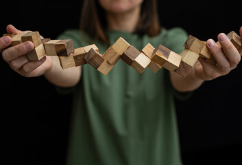 Wooden snake puzzle toy in the hands of a girl in a green T-shirt. Focus on toy.