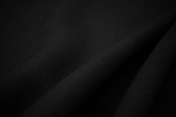 Texture of dark black fabric closeup. Low key photo. Plexus threads. Clothing industry. Abstract background. Black textile waves. Black cloth background