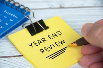 Year end review text on yellow notepad with December calendar background. Year end closing and review concept. - obrazy, fototapety, plakaty