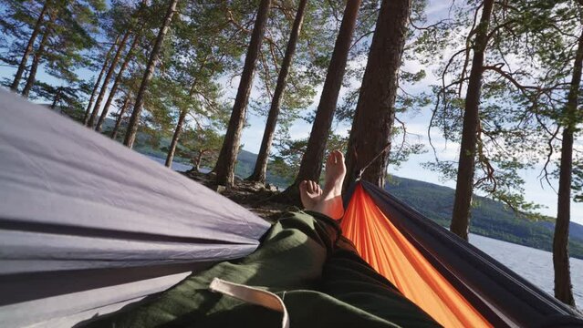 Male Feet Swinging In Orange Hammock Among The Beautiful Pine Forest. Pov Shot Of Hikers Mans Legs. First Person View