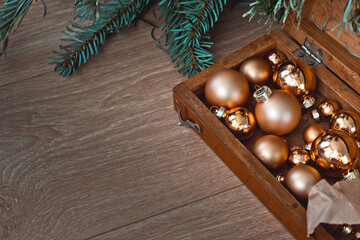 christmas golden balls in a wooden box. Christmas tree branches. The concept of a village Christmas. Background postcard. Wooden background. Horizontal image