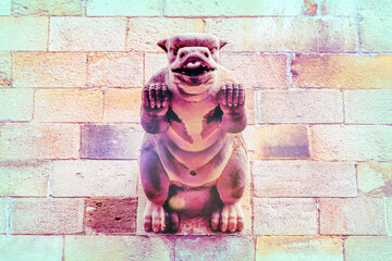Antique stone gargoyle decorating a medieval stone wall in the Gothic district in Barcelona, Spain