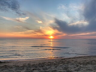 at the sea the red-golden sun shines out from behind the clouds before it sets