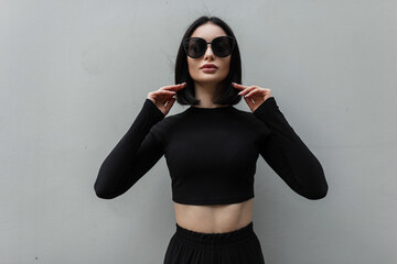 Stylish female urban portrait of a beautiful girl with trendy sunglasses in fashion black clothes...