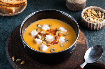 Pumpkin soup with feta and tomatoes. Soup with seeds. Carrot soup with cheese. Vegetarian soup.