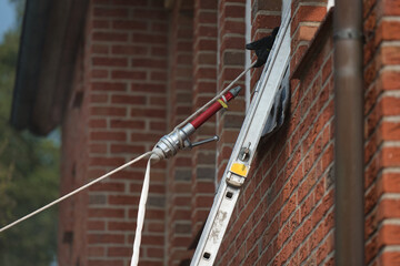 A jet pipe with a hose from the fire brigade is pulled up into the window using a line on a ladder