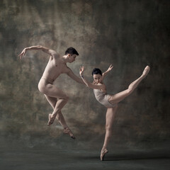Young man and woman, ballet dancers performing isolated over dark green vintage background. Pastel,...