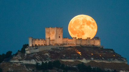 Full moon raising behind medieval Peñafiel Castle in Spain