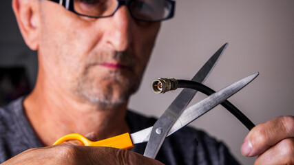 Man is cutting tv cable with scissors close up