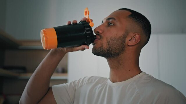 Closeup African American athlete bodybuilder sports man male drinking water from shaker in morning drink liquid calcium vitamins protein nutrition supplements aqua balance refreshment weight loss care
