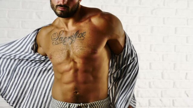 Young fit man opening sweater on naked muscular torso