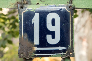 Weathered grunge square metal enameled plate of number of street address with number 19