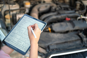 Action of the engineer is checking the car maintenance checklist in the digital tablet during...
