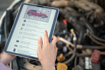 Using the vehicle checklist guideline on the digital tablet during perform preventive maintenance with car engine part as blurred background. Transportation service and maintenance working action. - obrazy, fototapety, plakaty