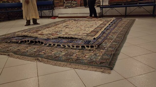 Shallow focus of a man rolling out amazing handmade rugs, from the biggest to the smallest