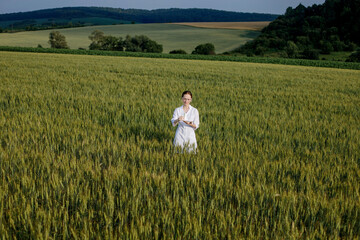 Scientist technologist in a white coat on a young wheat field writes down data on this year's crop...