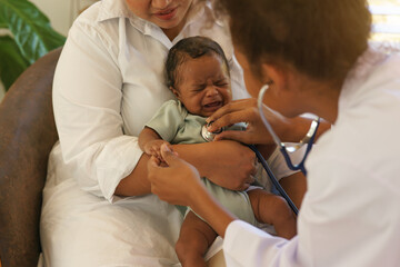 Obraz premium Newborn baby one-month-old mixed race African-Thai, crying sick visiting the doctor for checkup health with stethoscope at clinic pediatric. concept consultation, check-up, nurse, healing infant.