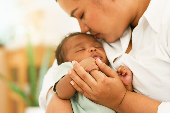 African Newborn baby one-month-old holding fingers mother's hand, sleep relax worry-free in warm embrace mom. image with a shallow depth of field, Select focus area hand. concept family mixed race. - Powered by Adobe