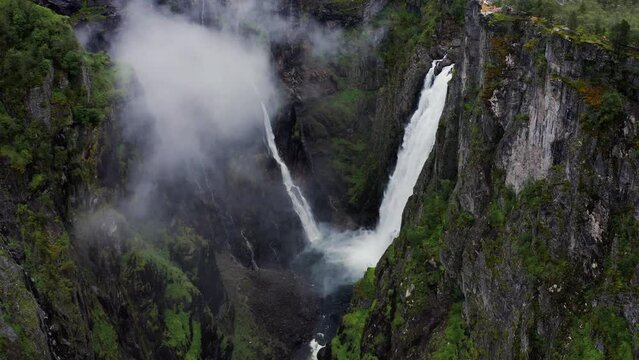 Voringfossen waterfall and sorrounding valley in rainy and fogy typical Norway weather captured by professional drone camera.