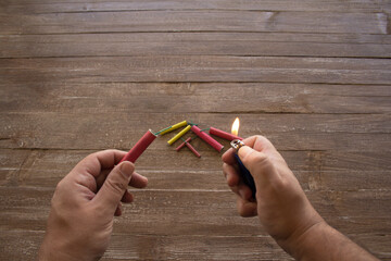Image of the hands of a man who lights the fuse of a firecracker with a lighter. Reference you have...