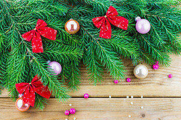 Top view of Christmas (New Year) decoration composition: fur-tree branches, pink and golden glass balls on wooden background