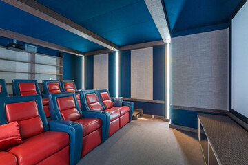 The interior of a private home theater, decorated in gray and blue. Two rows of comfortable chairs.