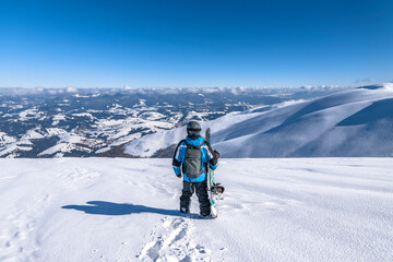 Snowboarder with snowboard in hand on mountain top. Winter freeride snowboarding