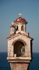 Verticale close-up shot van een kleine sculptuur van een kerk tegen de achtergrond van de zee