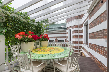 A terrace at the house with a gazebo covered with ivy. White garden furniture. A cozy place to relax on a summer day.